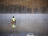 Man fishing on foggy lake Photographie par David Stoecklein
