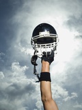 Football player holding helmet in air Photographic Print by Erik Isakson