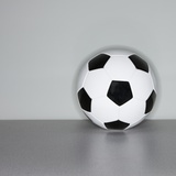 Soccer ball next to wall Photographic Print