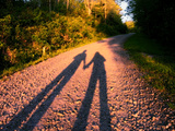 The Long Shadow of a Couple Holding Hands Cast on a Dirt Road Photographie par Amy & Al White & Petteway