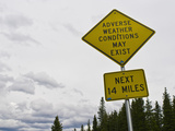 A Road Sign Warns of Adverse Weather Conditions Along the Continental Divide Photographic Print by Jon Van de Grift