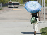 A Woman Wears Loose Fitting Clothing and Carries an Umbrella to Block the Sun During Heat Wave Fotografie-Druck von Jon Van de Grift