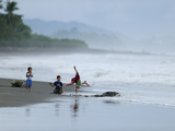 Kids Playing on the Beach While Olive Ridley Sea Turtle Come Ashore Photographic Print by Solvin Zankl