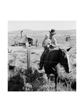 Cowboy Holds His Baby While Riding a Horse Prints by Dorothea Lange