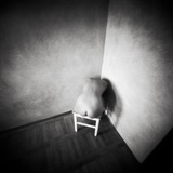 A Naked Female Figure Sitting on a Stool in the Corner of an Empty Room Photographic Print by Rafal Bednarz