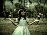 A Young Girl with Long Dark Hair Dressed in White Wearing Gloves Looking at White Butterflies Photographic Print by Cristina Carra Caso