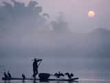 A Fisher Uses Cormorants to Capture Fish from the Li River at Sunrise Photographic Print by Kenneth Ginn