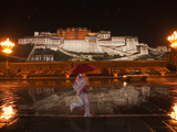 A Pedestrian in Front of the Potala Palace on a Rainy Night Photographic Print by Michael S. Yamashita