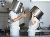 Two Chefs Having Discussion with Large Pans on their Heads Photographic Print by Robert Kneschke