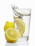 A Wedge of Lemon Falling into a Glass of Water Photographic Print by  Kröger & Gross