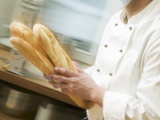Chef Hurrying Through Kitchen with Baguettes Photographic Print
