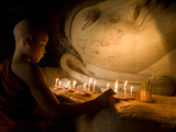 A Novice Monk Lighting Candles at a Massive Buddha Statue in Burma (Myanmar) Photographic Print by Kyle Hammons