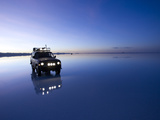 A 4X4 Rests in the Early Am Reflection in a Flooded Salt Flat In Photographic Print by Sergio Ballivian