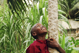 Schoolchild Embracing Tree Trunk and Looking Up, Bujumbura, Burundi Photographie par Anthony Asael