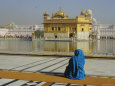A Pilgrim in Blue Sits by the Holy Pool of Nectar at the Golden Temple, Punjab, India Photographic Print by Jeremy Bright