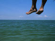 Sandy Feet Dangle Off the Side of a Dock on Portsmouth Island Photographie par Stephen Alvarez